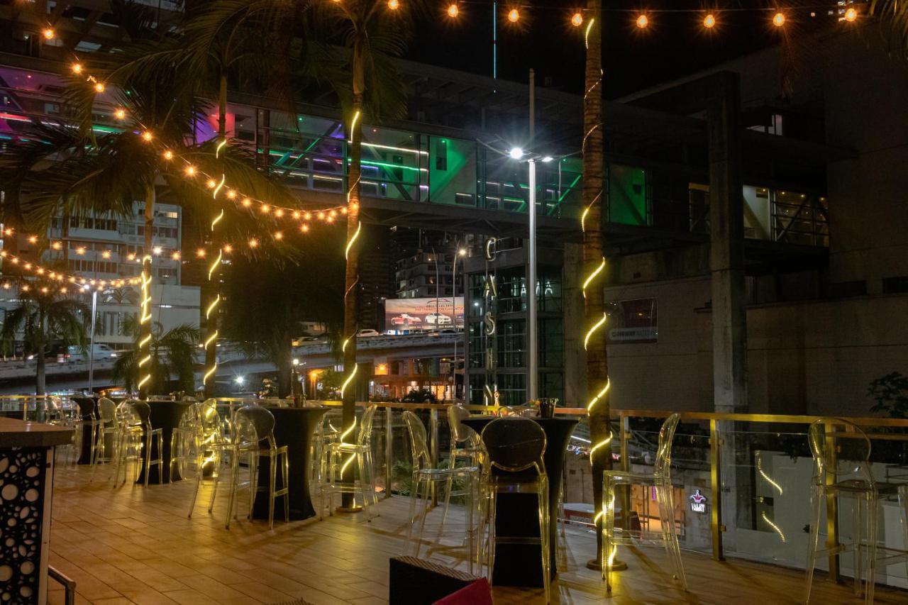 Decapolis Hotel פנמה סיטי מראה חיצוני תמונה The photo shows an outdoor seating area, likely at a restaurant or bar. It features several tall tables with transparent chairs around them. The space is illuminated with string lights that create a warm and inviting atmosphere. In the background, th