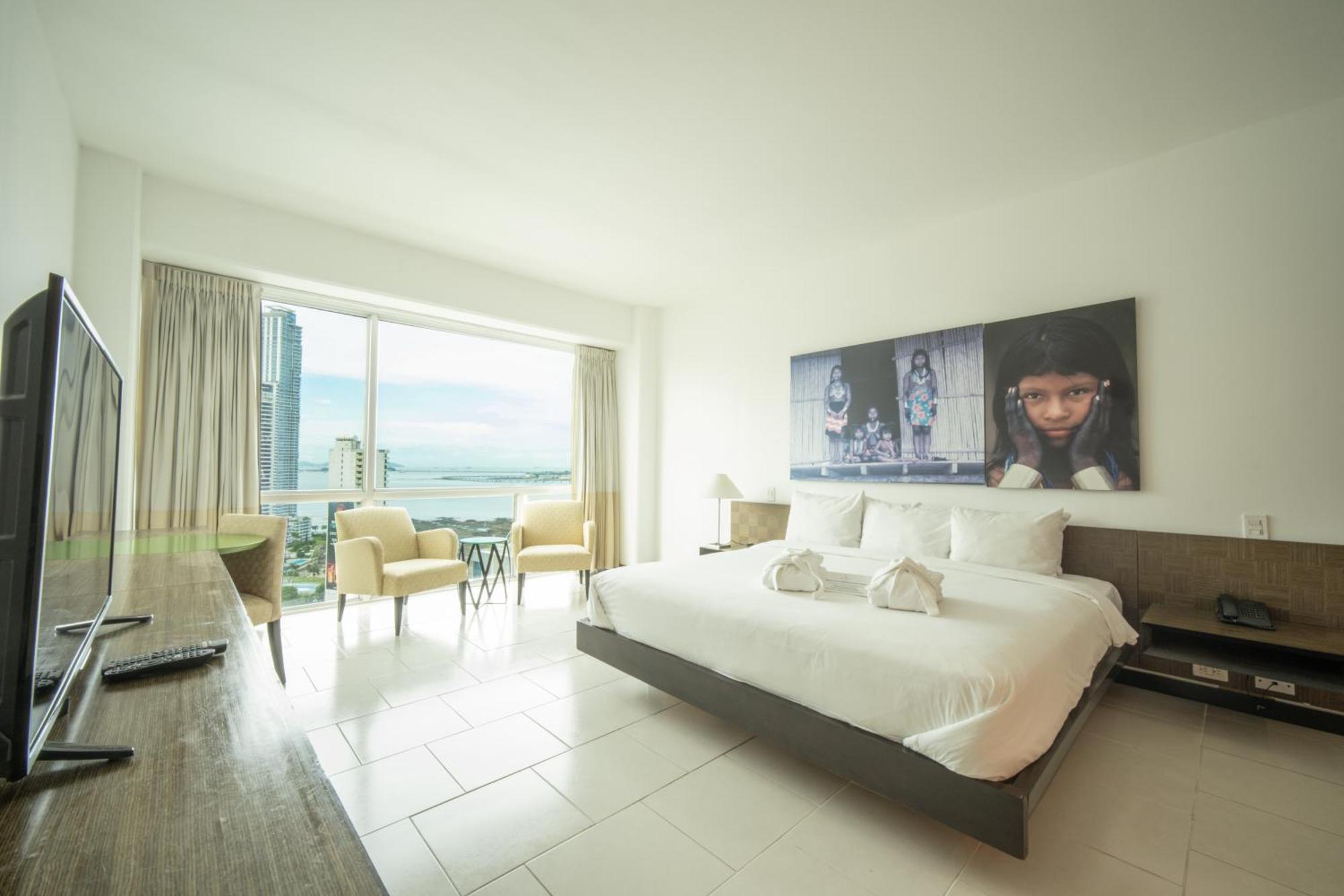 Decapolis Hotel פנמה סיטי מראה חיצוני תמונה The photo showcases a modern hotel room. It features a large bed with white linens and decorative towels arranged neatly. Behind the bed, there's a large artwork or photo displayed on the wall. The room has a large window that allows natural light to